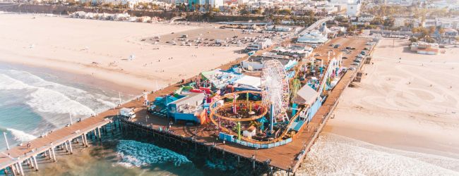 Aerial view of a harbor with piers, boats, and turquoise water; sunlit marina and coastline scenery.